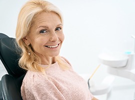 Smiling woman in light pink shirt in dental chair